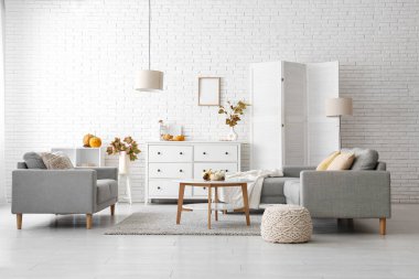 Sonbahar dekoru, kanepeleri ve çekmeceleri olan aydınlık oturma odasının içinde.