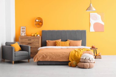 Sonbahar dekoru olan şık bir odada büyük, rahat bir yatak.