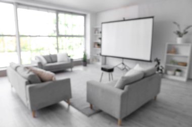 Projektör ekranlı, raf üniteli ve kanepeli ışık odasının bulanık görüntüsü