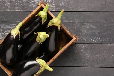 Siyah ahşap arka planda taze patlıcanlı kutu.