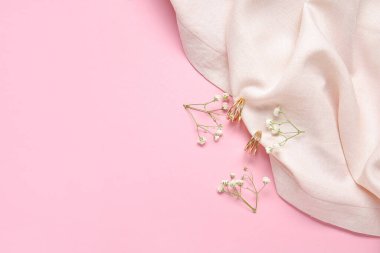 Pembe arka planda çingene çiçekli ve kumaşlı güzel altın küpeler.