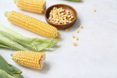 Taze mısır koçanları ve beyaz masada çekirdekleri olan ahşap kase.