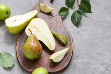 Gri masa üzerinde olgun armutlar olan ahşap tahta, yakın plan.