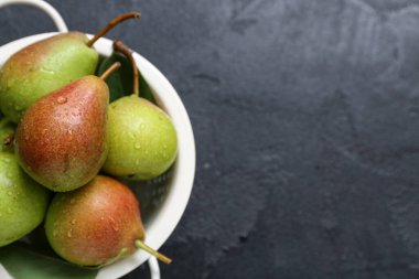 Siyah masada olgun armutlarla Colander, yakın plan.