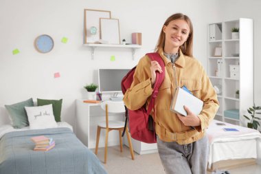 Yurt odasında kitap ve sırt çantası olan bir kız öğrenci.