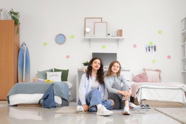 Yurt odasında yerde oturan kız öğrenciler.