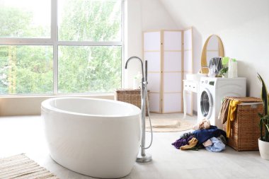 Küvetli, çamaşır sepetli ve çamaşır makineli hafif banyonun içi.