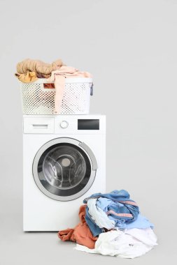 Kirli çamaşırlı çamaşır sepeti ve arka planda çamaşır makinesi.