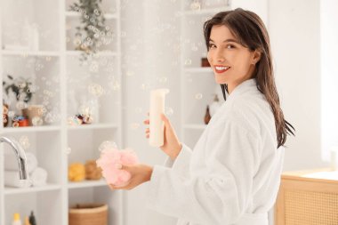 Bornozlu, güzel, genç bir kadın. Duş almadan önce jöle ve sünger kullanıyor.