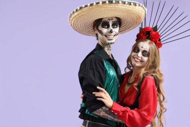 Mor arka planda Meksika Ölüler Günü (El Dia de Muertos) için giyinmiş genç mutlu çift