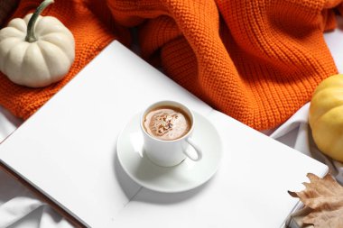 Evde bir fincan lezzetli kabak kahvesi, kitap ve sıcak süveter.