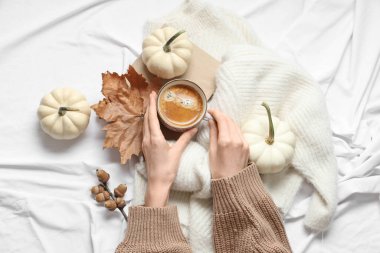Lezzetli balkabağı kahveli kadın elleri, sonbahar süslemeleri ve evdeki sıcak süveter, üst manzara.