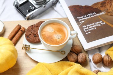 Kurabiyeli bir fincan lezzetli balkabağı kahvesi, sonbahar süslemeleri, yatakta kamera ve dergi.