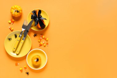 Cadılar Bayramı kutlaması için turuncu arka planda hediyeler, şekerler ve balkabaklarıyla şenlik masası.