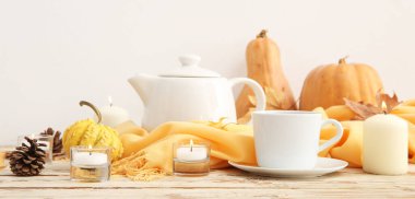 Çay, eşarp, çaydanlık, balkabağı ve sonbahar yapraklarıyla yanan mumlar beyaz arka planda