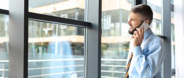 İş adamı ofiste cep telefonuyla konuşuyor.