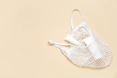 Bej arka planda kozmetik ürünler içeren ağ torbası