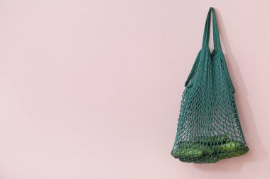 Odadaki bej duvarda asılı salatalıklı ağ torbası.