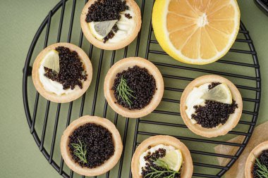 Yeşil arka planda siyah havyarlı lezzetli tartların ızgarası.