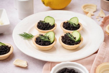 Hafif arka planda siyah havyarlı lezzetli tart tabağı.