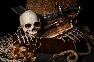 Seyahat ekipmanlı korsan sandığı, altın külçeler, siyah arka planda insan kafatası ve ağ