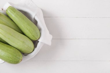 Beyaz ahşap arka planda yeşil kabaklı bir kase.