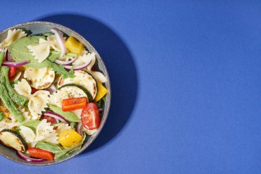 Kırmızı soğanlı ve biberli bir tabak lezzetli makarna salatası.