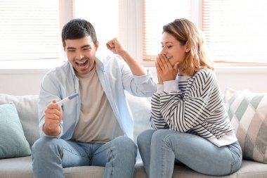 Evde hamilelik testi olan mutlu genç bir çift.