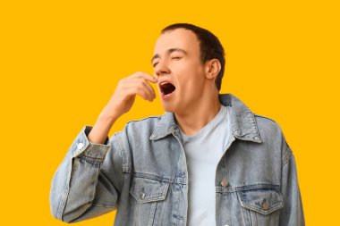 Sarı arka planda hapşıran hasta genç adam.