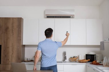 Yakışıklı adam mutfaktaki klimayı açıyor, arkadan bakıyor.