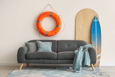 Ekoseli, yastıklı, sörf tahtalı ve can simidi yüzüklü rahat bir kanepe.