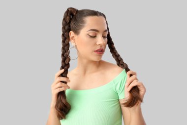 Gri arka planda örgüleri olan güzel bir genç kadın.