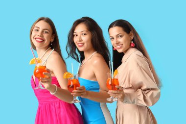 Mavi arka planda aperol spreyli güzel genç kadınlar.