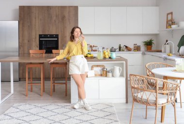 Genç bayan mutfakta limonata içiyor.