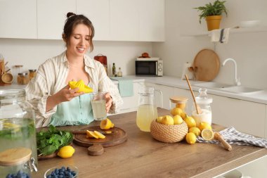 Genç kadın mutfakta limonata yapıyor.