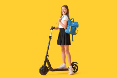 Sarı arka planda elektrikli scooter 'ı olan tatlı bir kız öğrenci.