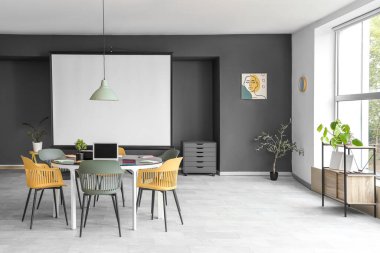 Masa ve projektör ekranlı konferans odasının içi