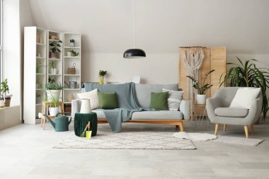 Interior of living room with green plants, sofa and armchair