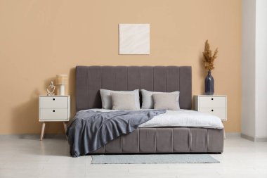 Rahat yatağı, komodinleri ve vazo dolusu otları olan güzel bir yatak odası.