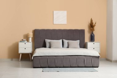 Rahat yatağı, komodinleri ve vazo dolusu otları olan güzel bir yatak odası.