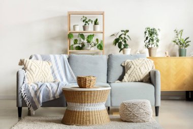 Oturma odasının içinde kanepe, masa ve bitkiler var.