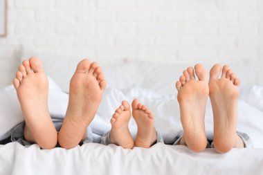 Küçük kızın ayakları ve ailesi yatak odasında battaniyenin altında yatıyorlar.