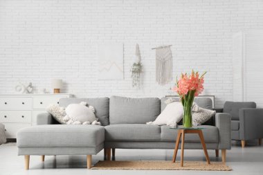 Oturma odasının içinde, masasında vazo ve gladiolus çiçekleri olan bir masa.