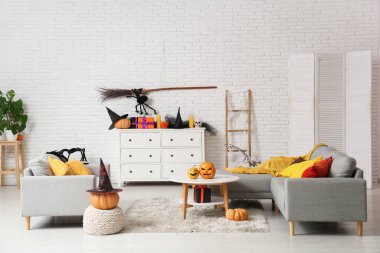 Cadılar Bayramı için dekore edilmiş oturma odasının içi kanepe, masa ve çekmecelerle dolu.