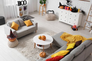 Cadılar Bayramı için dekore edilmiş oturma odasının içi kanepe, masa ve çekmecelerle dolu.