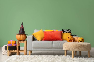 İçinde kanepe, Cadılar Bayramı balkabağı ve hediyeler olan bir oturma odası.