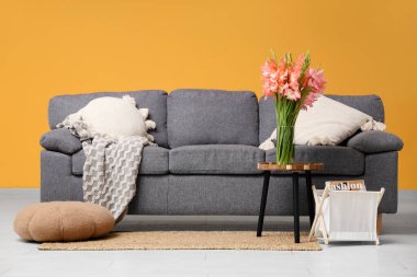 Kanepe ve vazoda gladyatör çiçekleri olan şık bir oturma odası.