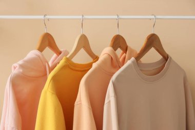 Bej duvarın yanında kazaklı raflar, yakın plan.