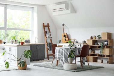 Mutfağın içinde tezgahlar, yemek masası ve bitkiler var.