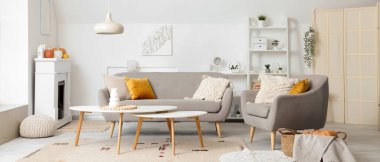 Elektrikli şöminesi, gri koltuğu ve kanepesi olan aydınlık oturma odasının içinde.